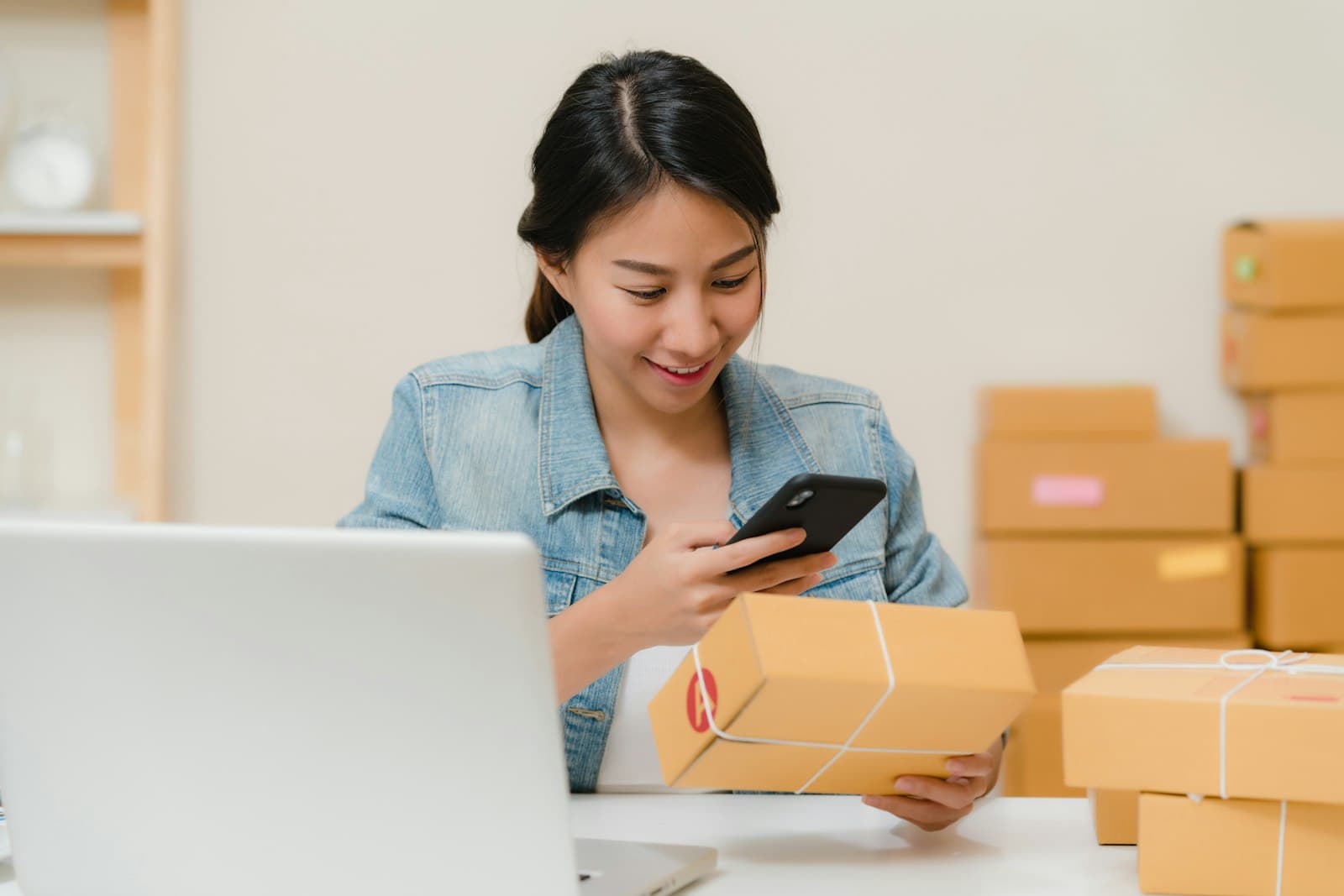 Persona revisando un paquete de su tienda online junto a la laptop