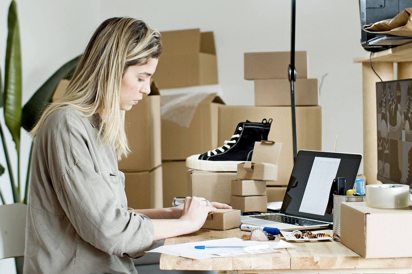 Persona armando un pedido de su tienda online rodeada de cajas de stock